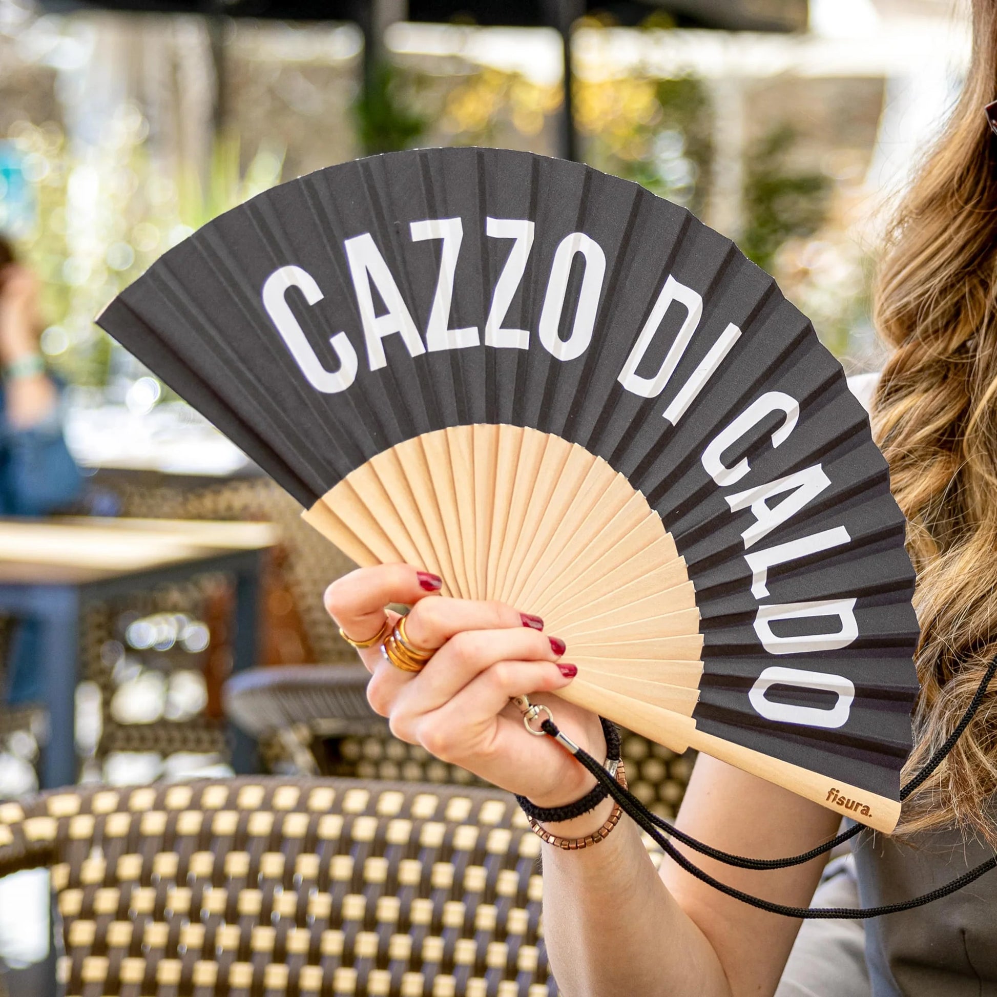Donna in bar con appeso al collo il ventaglio cazzo di caldo nero, laccetto nero. 