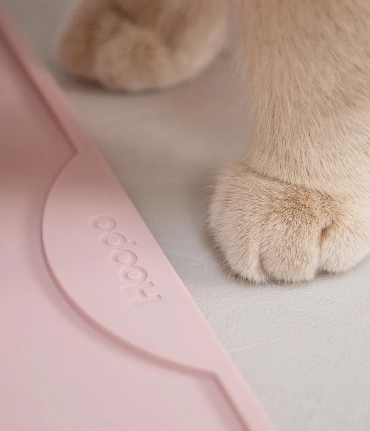 Zampe gatto e scritta Hoopo su tappetino rosa in silicone. Sfondo grigio