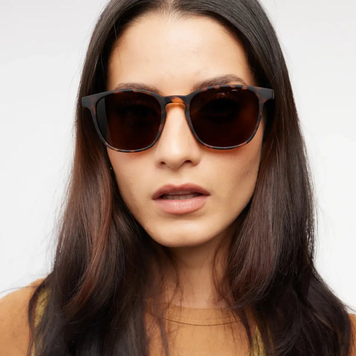 Occhiale da sole marrone design tartaruga finitura opaca, indossato da donna mora.