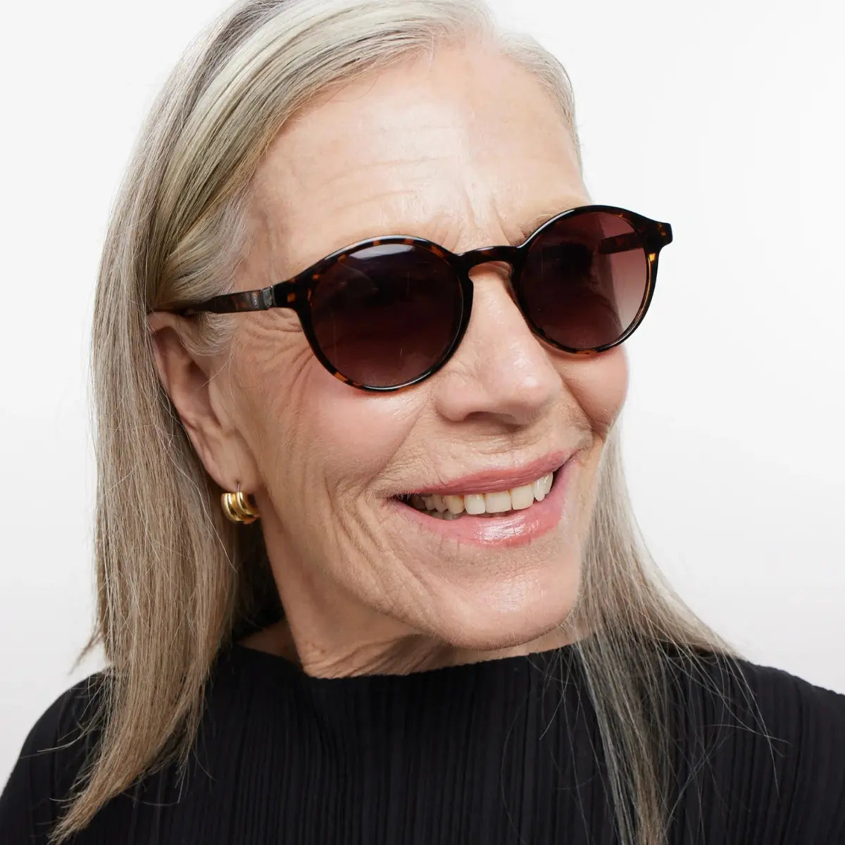 Occhiale marrone design tartaruga finitura lucida, con lenti scure indossato da donna bionda.
