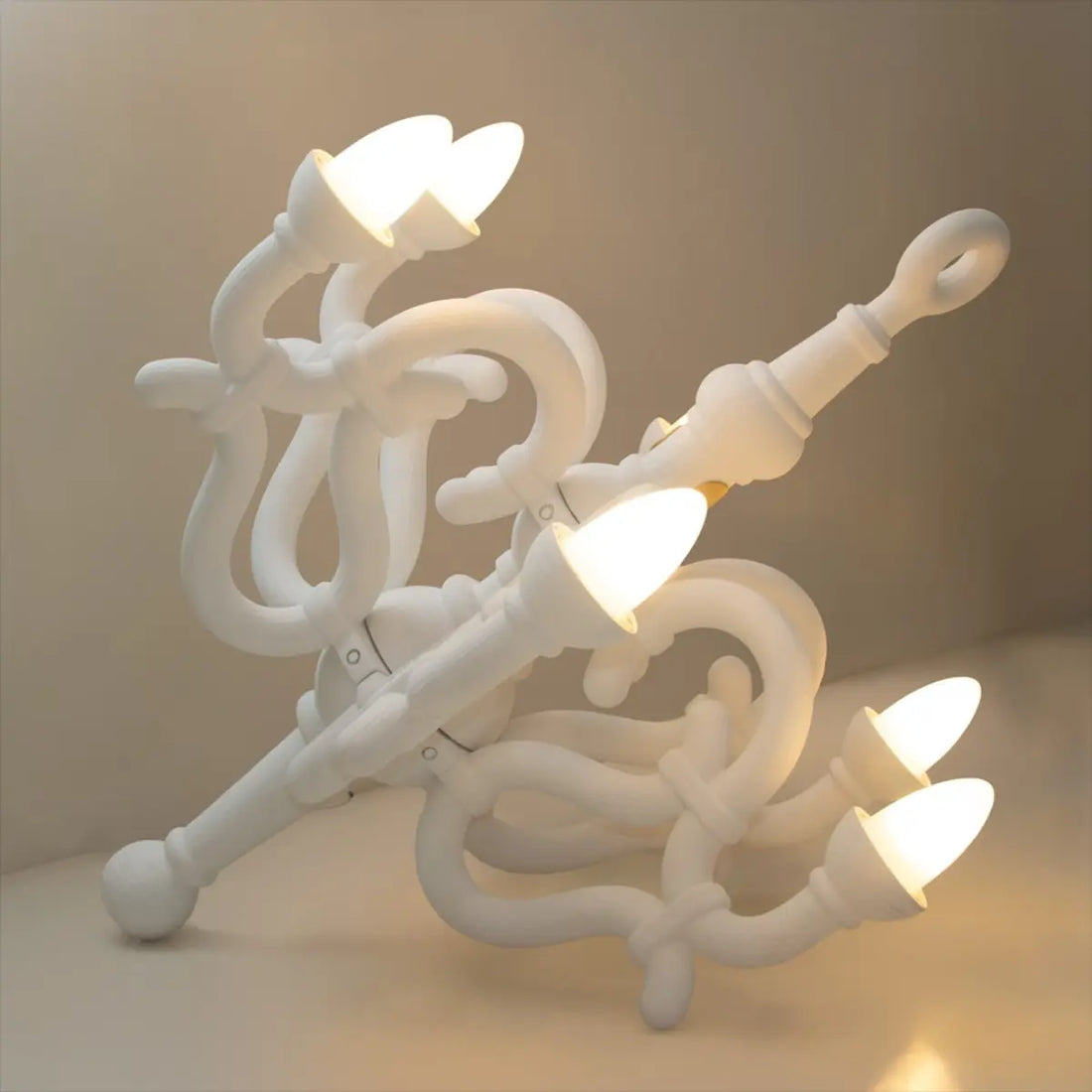 Lampada da terra bianca a forma di candelabro classico. La lampada è appoggiata a terra in una stanza con parete e muro bianco. Le 6 lampadine led sono accese e fanno una luce diffusa nell'ambiente