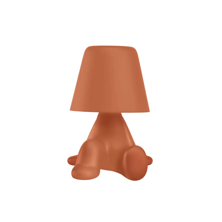 Lampada arancione con struttura a forma di personaggio seduto con la testa a forma di paralume

