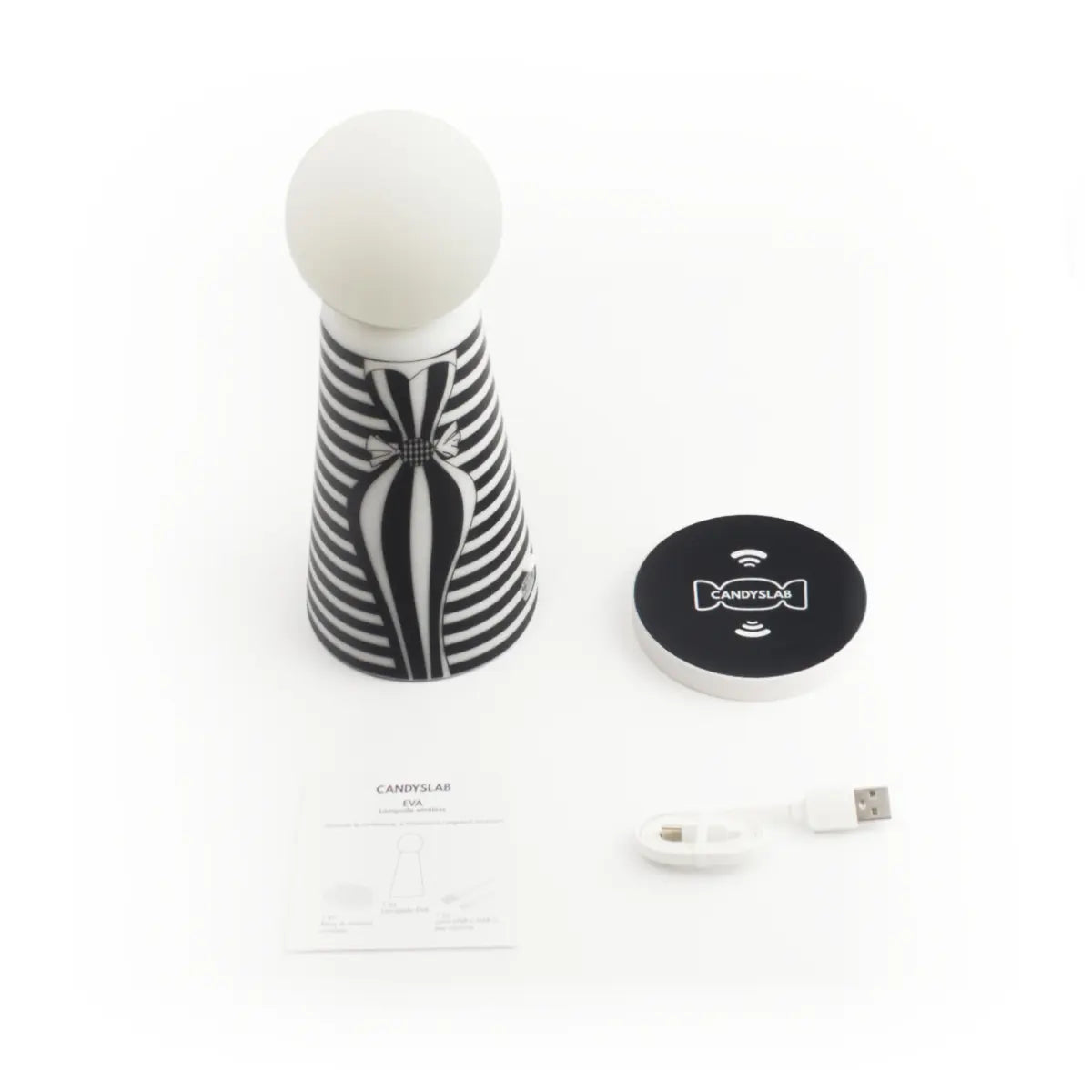 Contenuto della confezione della lampada da tavolo Eva. Contiene la lampada a righe, la base di ricarica wireless, il cavetto di ricarica e il libretto delle istruzioni. Sfondo bianco 