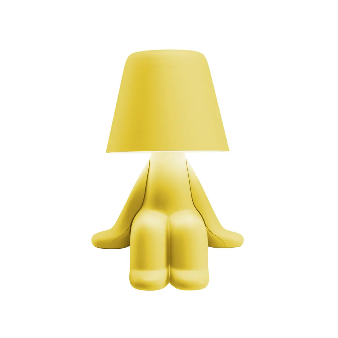 Lampada gialla a forma di personaggio stilizzato seduto, con la testa a paralume