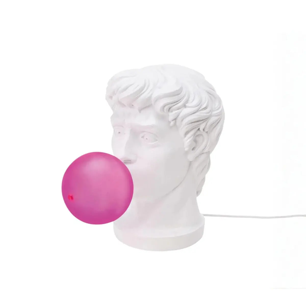 Lampada di resina bianca che rappresenta il viso di un giovane ragazzo che fa una bolla di chewing-gum fucsia che diventa la lampadina. Sfondo bianco 