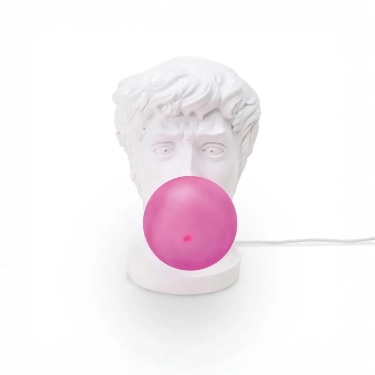 Lampada di resina bianca che rappresenta il viso di un giovane ragazzo che fa una bolla di chewing-gum fucsia che diventa la lampadina. Sfondo bianco 