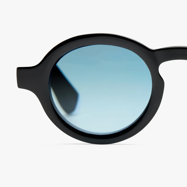 Dettaglio lente occhiale da sole montatura nera lente azzurra. Sfondo bianco