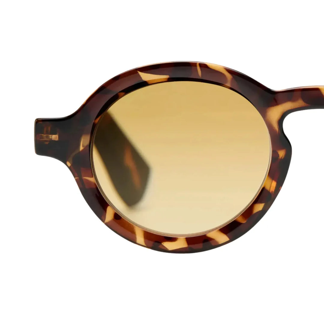 Dettaglio lente occhiale da sole montatura tortoise lente gialla. Sfondo bianco