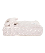 Cuccia letto per cani beige con pois bianchi e cuscino a forma di osso, vista laterale sfondo bianco.