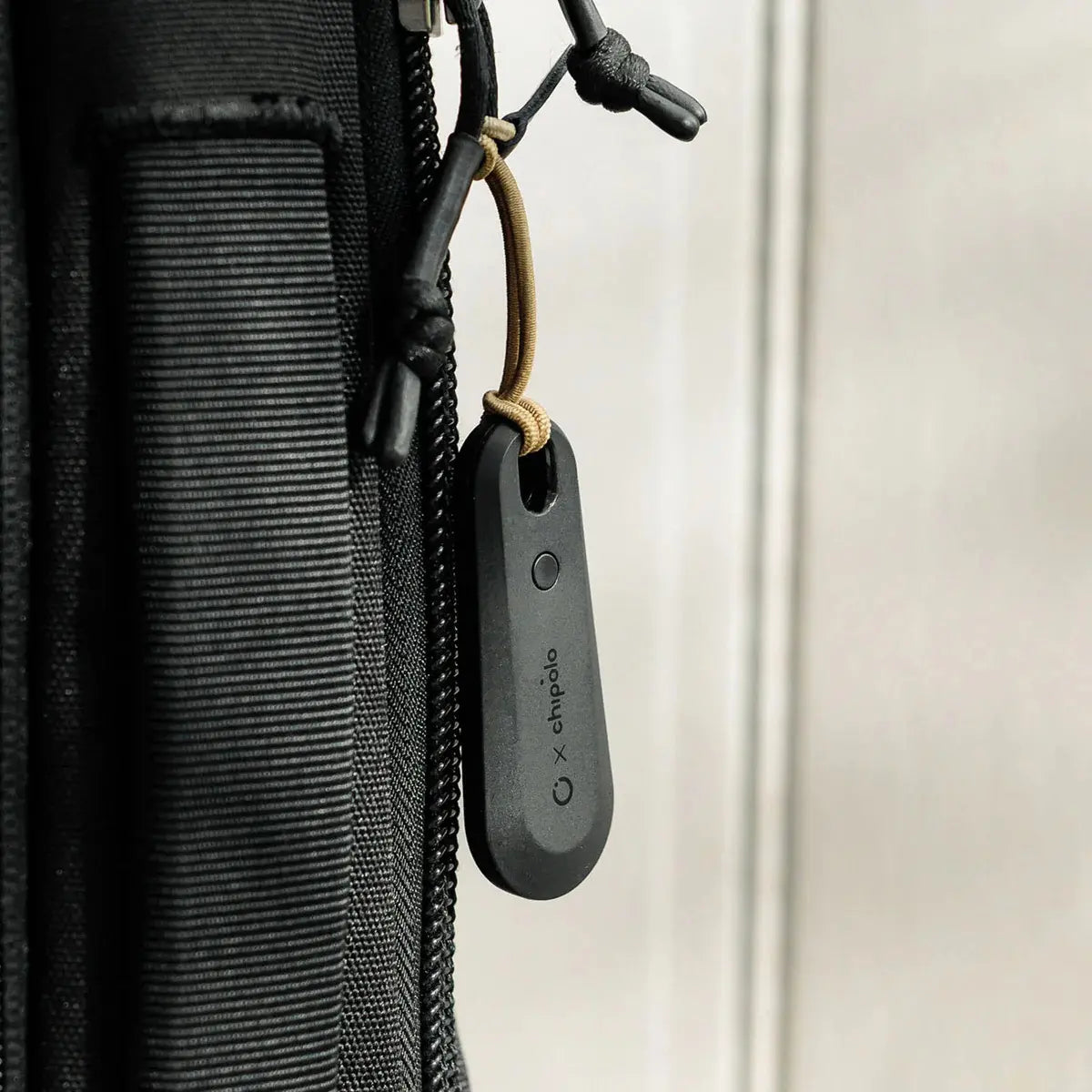 Localizzatore bluetooth Orbitkey nero appeso ad uno zaino attraverso il laccio elastico 