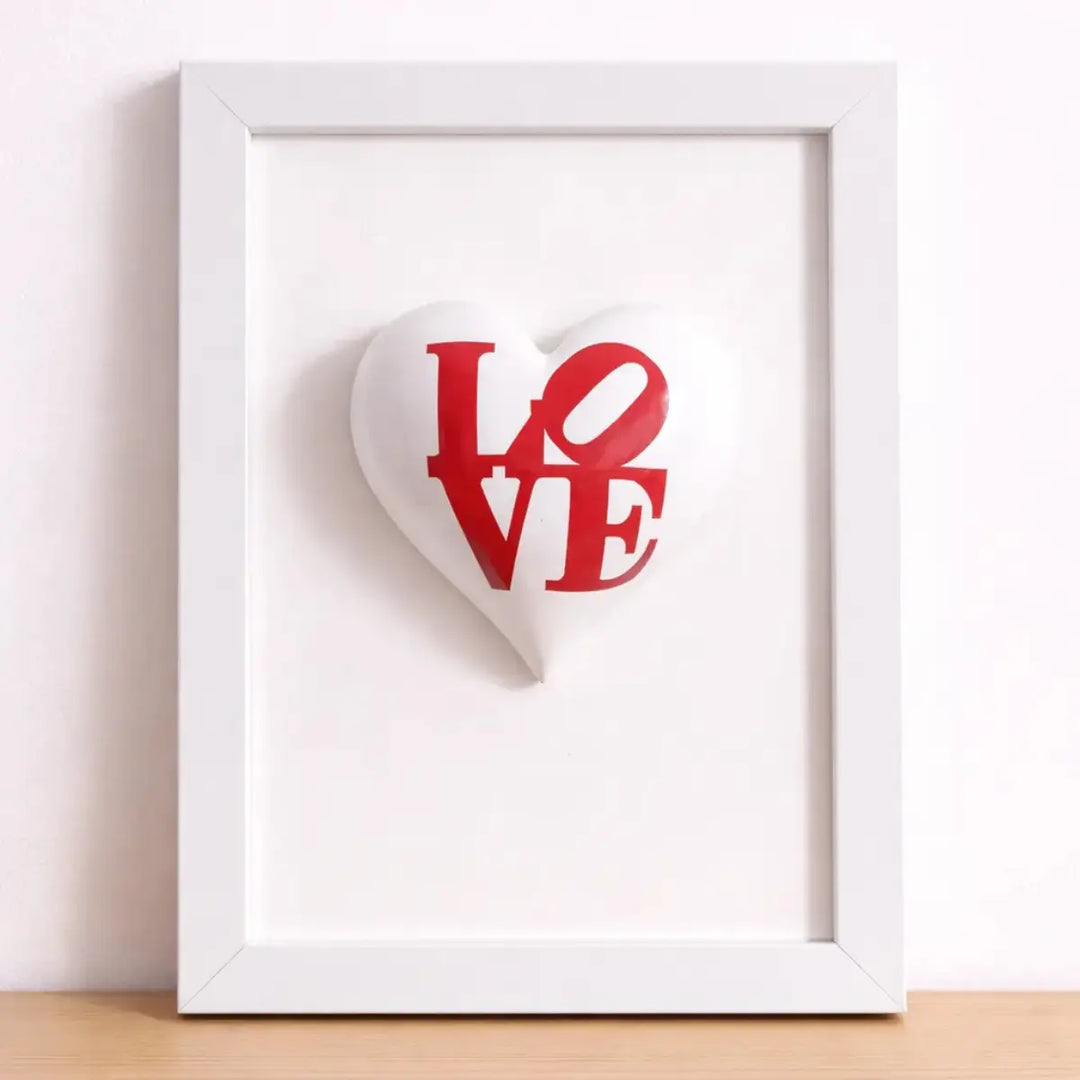 Quadretto CuoreAmore fatto a mano in Italia. Ha una cornice in legno bianca e un cuore in ceramica rosso con una scritta  