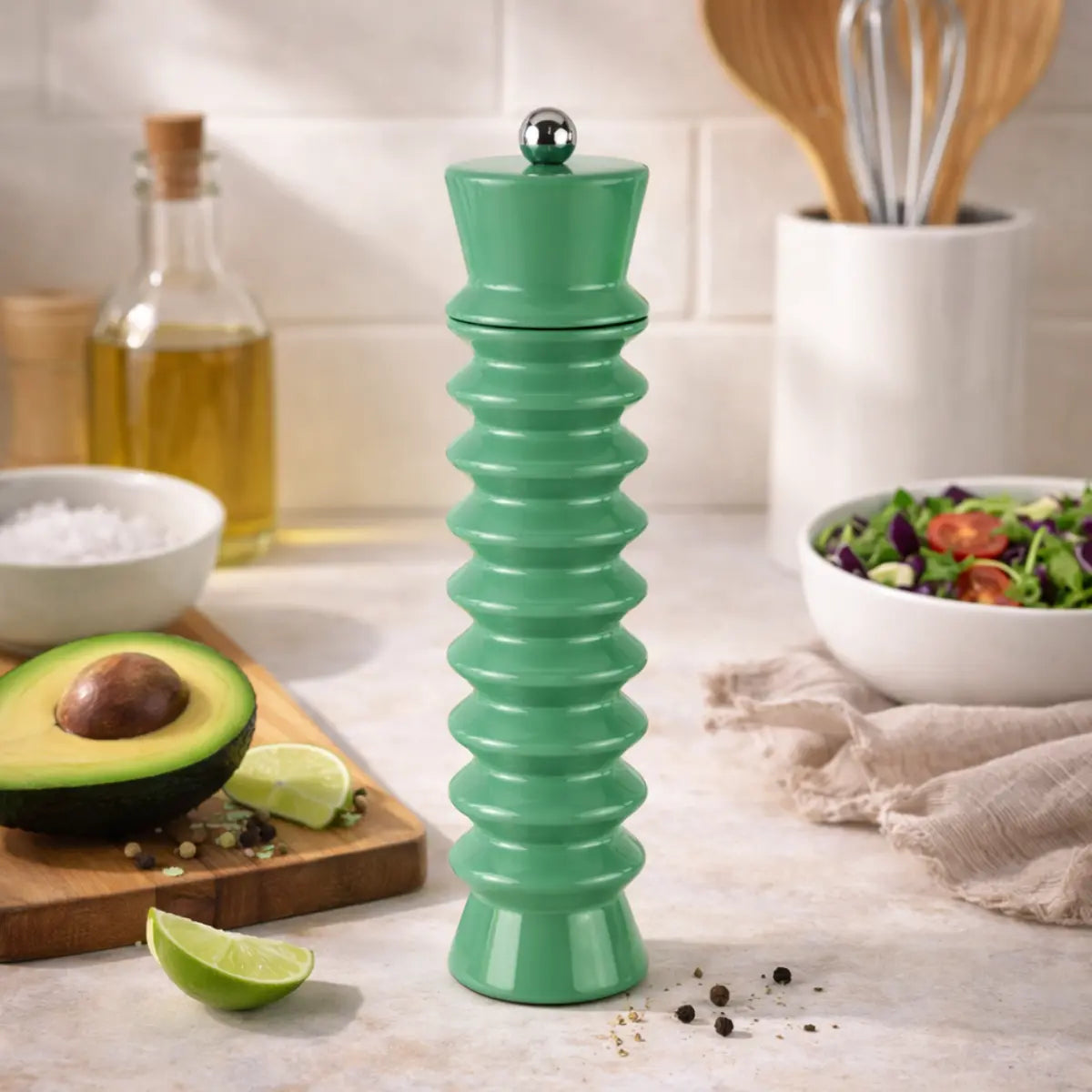 Macina sale e pepe verde salvia con forma geometrica posizionato in cucina accanto ad un tagliere. 