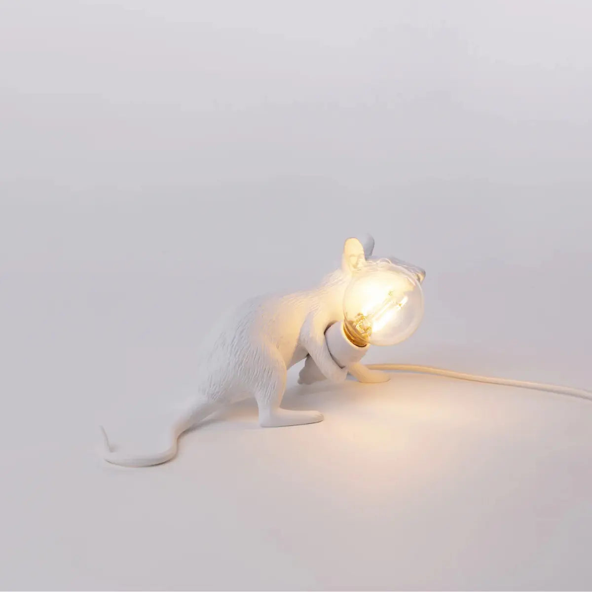 Lampada in resina bianca a forma di topo che tiene in mano una lampadina accesa. Sfondo bianco 