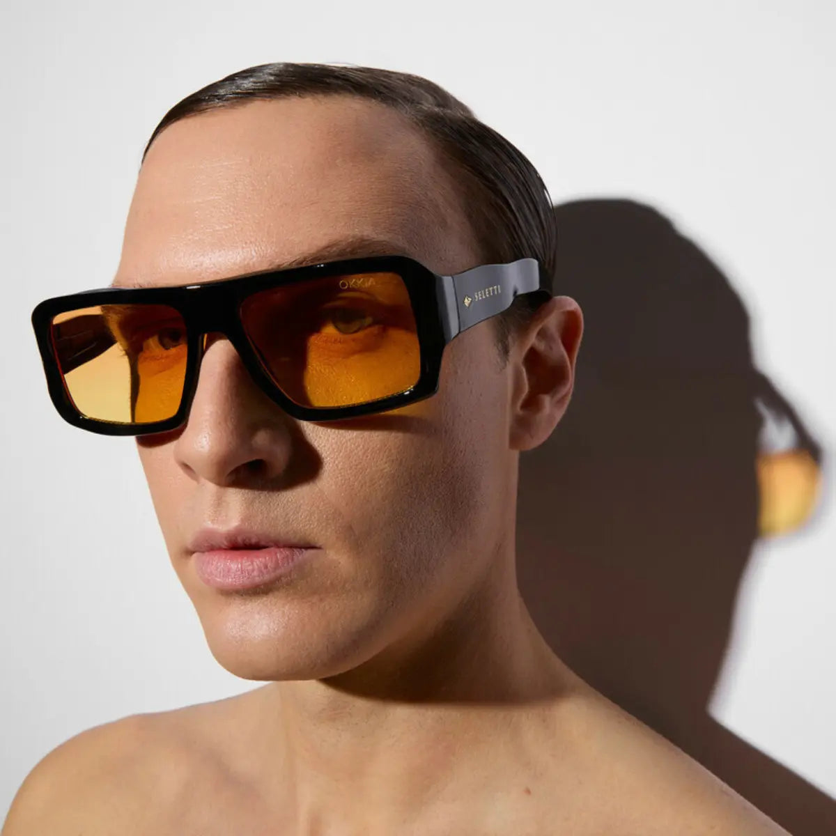 Modello che indossa gli occhiali da sole nel modello Kansas nero con lente giallo della collaborazione Okkia x Seletti