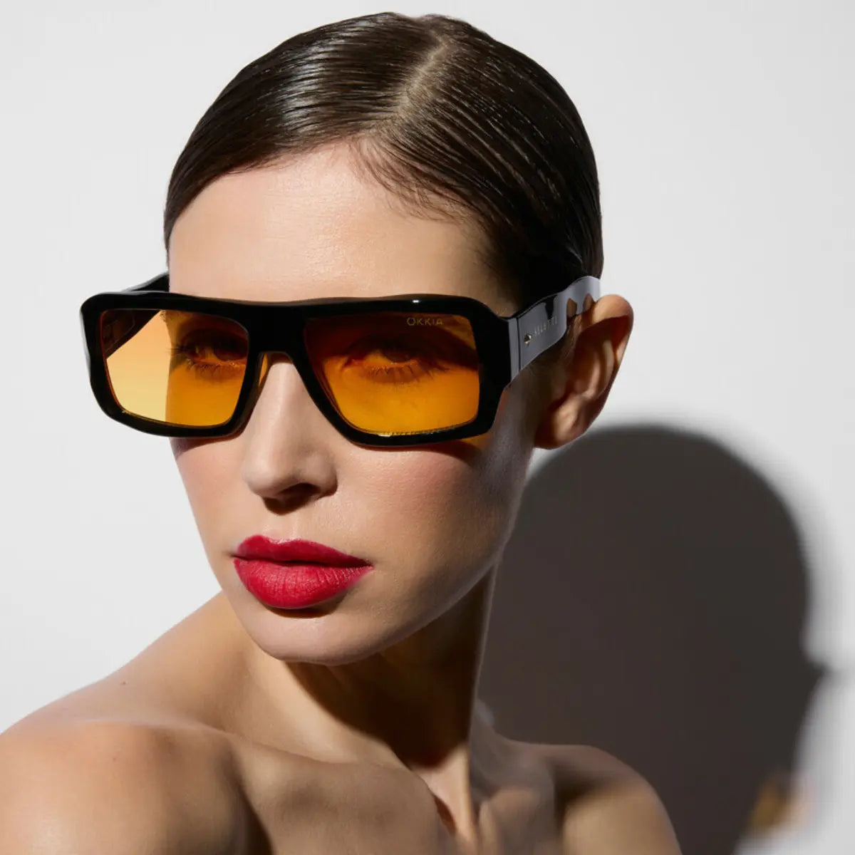 Modella che indossa gli occhiali da sole nel modello Kansas nero con lente giallo della collaborazione Okkia x Seletti