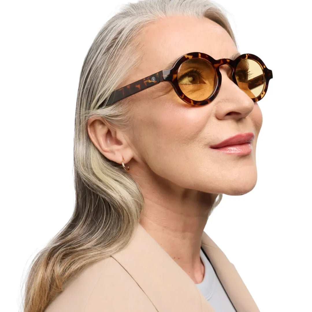 Donna che indossa occhiale da sole montatura tortoise con lente gialla. Sfondo bianco