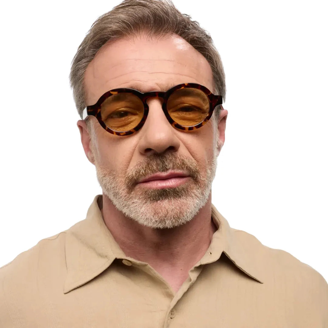 Uomo che indossa occhiale da sole montatura tortoise con lente gialla. Sfondo bianco