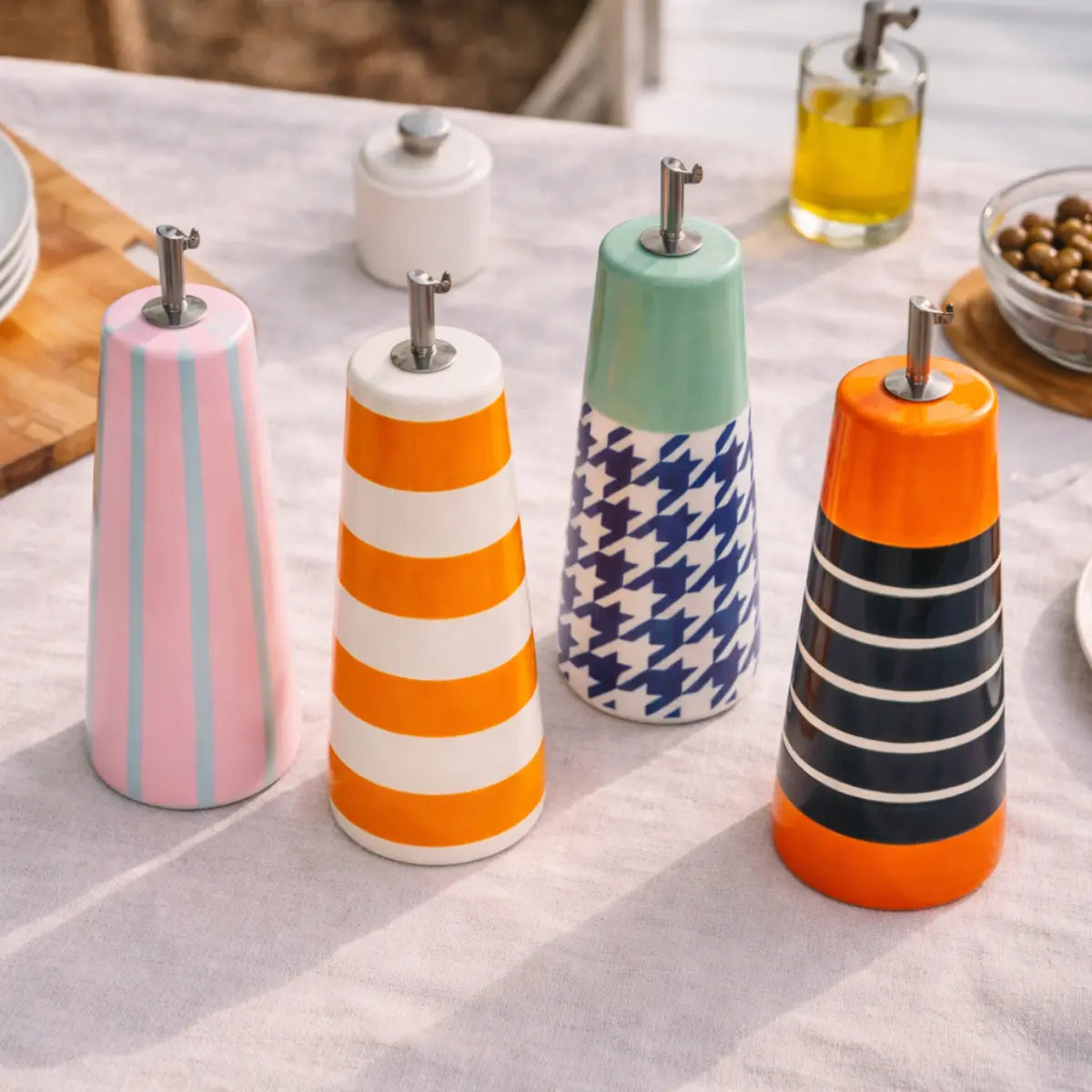 4 oliere colorate della collezione Sintra di Wd posizionate su un tavolo con tovaglia bianca.