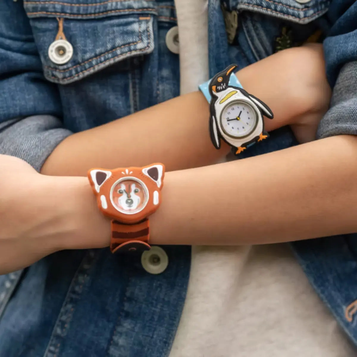 Bambino con le braccia conserte e ai polsi due orologi slap rappresentanti un pinguino e un panda rosso