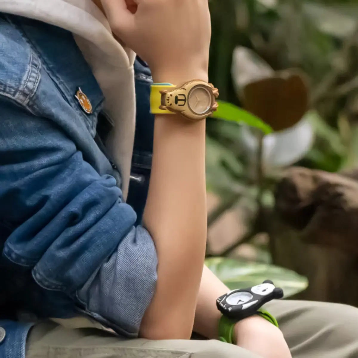 Bambino seduto con ai polsi gli orologi slap con due animali, il capybara e il panda. 