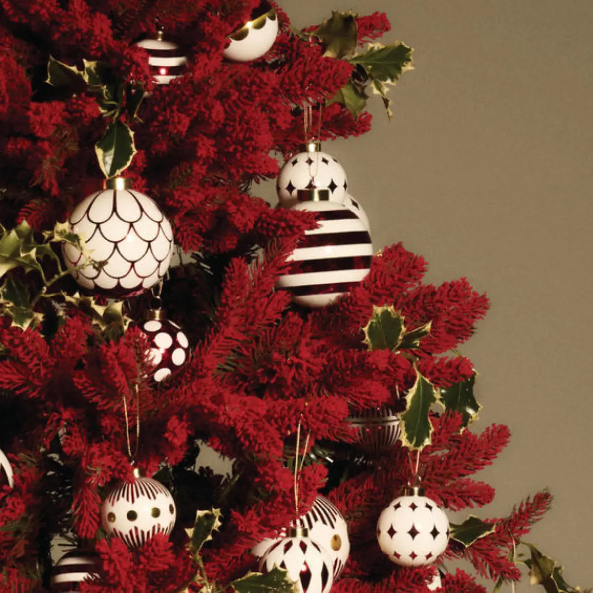 Varie palline di Natale Delight di Alessi su un albero di Natale rosso e verde.