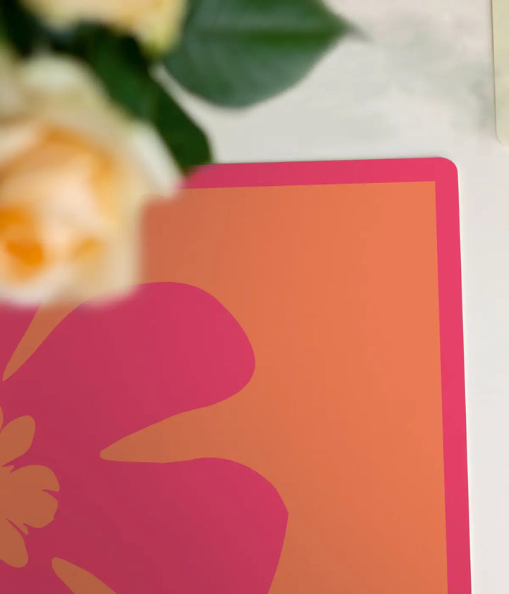 Angolo tovaglietta fucsia e arancione e fiore. Sfondo bianco