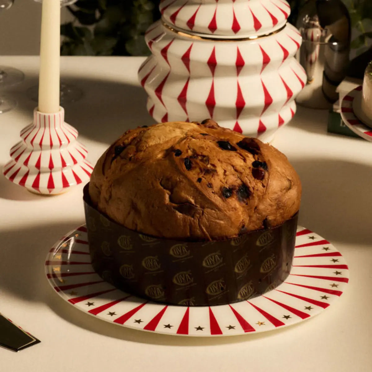 Piatto per panettone natalizio su tavola addobbata con portacandele e biscottiera