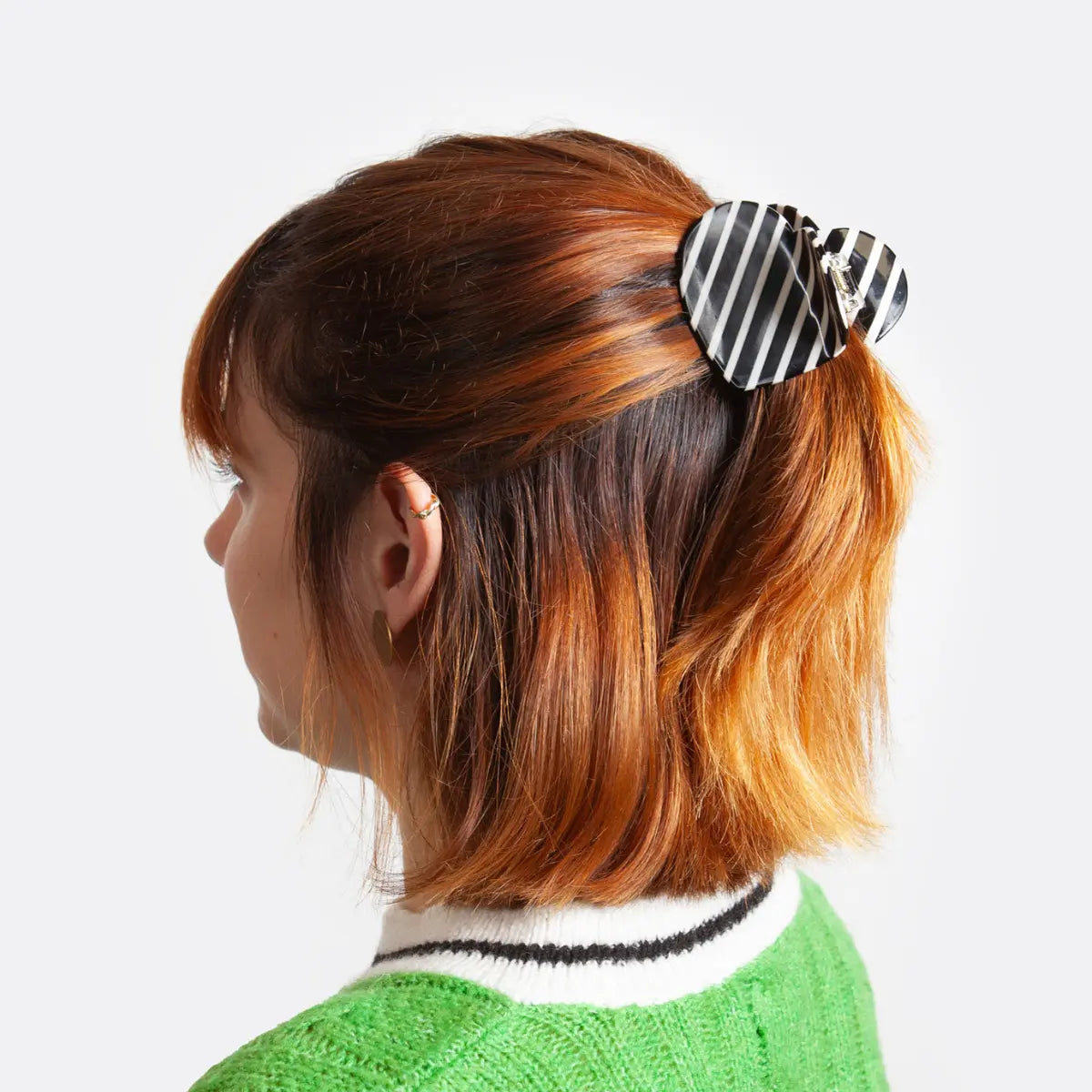 Pinza per capelli a forma di cuore con righe bianche e nere indossata su capelli di media lunghezza