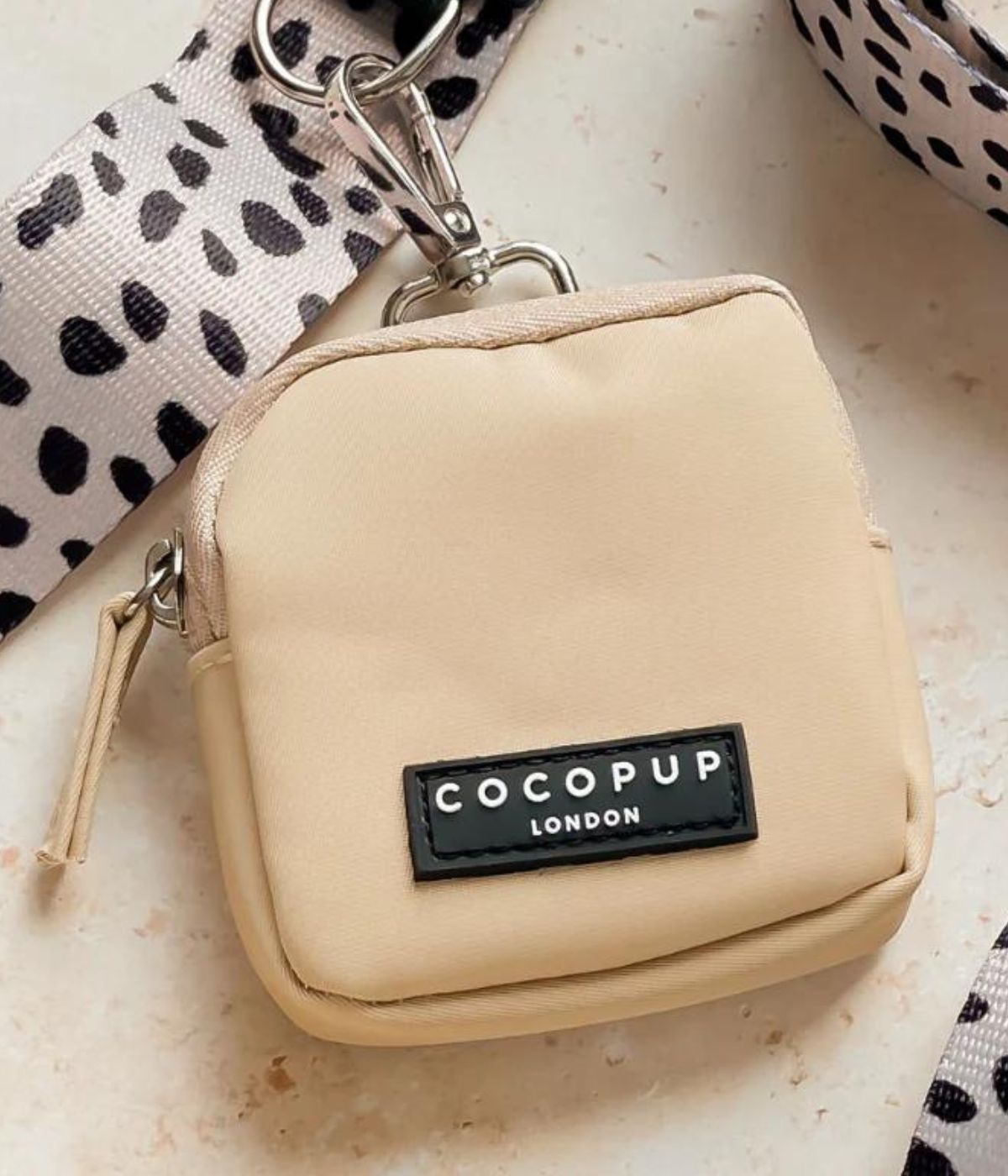 Porta snack crema su sfondo chiaro. Tracolla e moschettone.