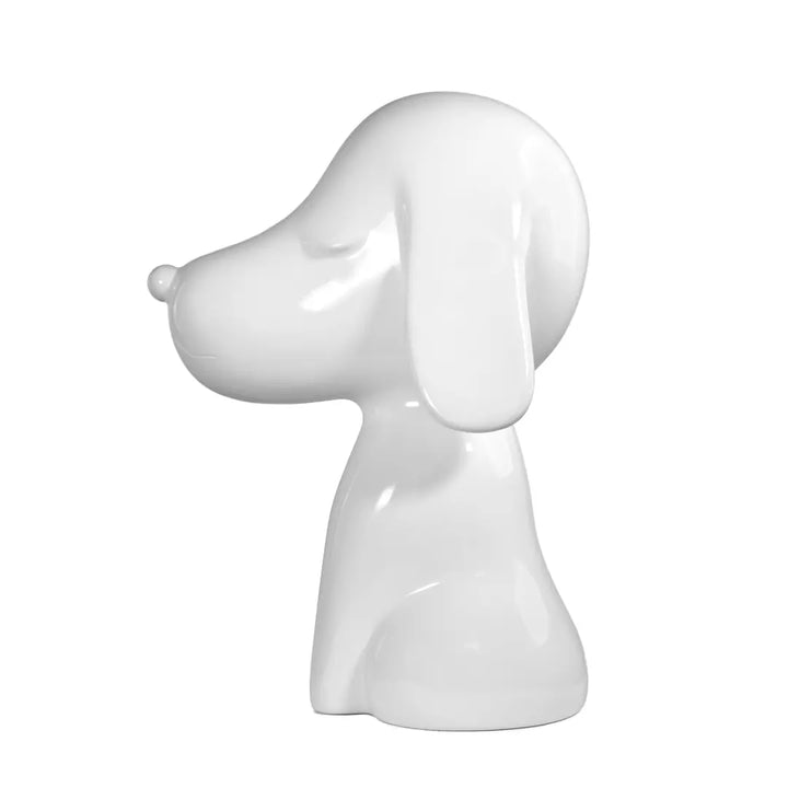 Profilo statua bianca a forma di cane, con occhi naso e bocca. Sfondo bianco