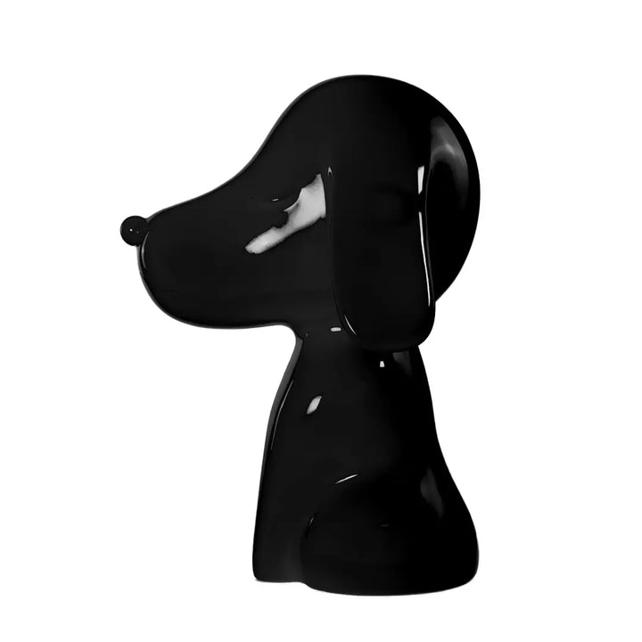 Profilo statua nera a forma di cane, con occhi naso e bocca. Sfondo bianco
