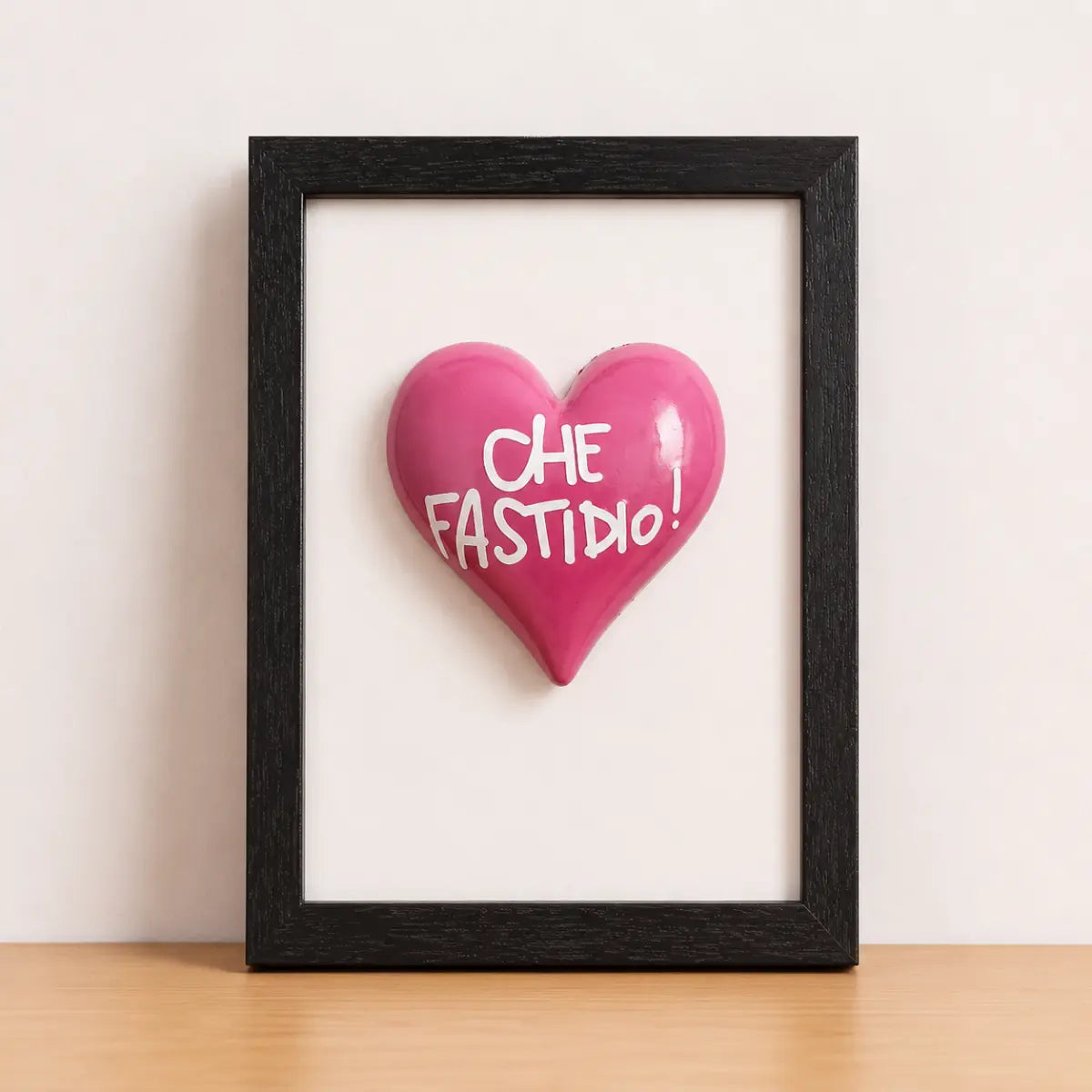 Quadretto realizzato a mano in Italia con cornice nera e al centro un cuore rosa con scritta "che fastidio"