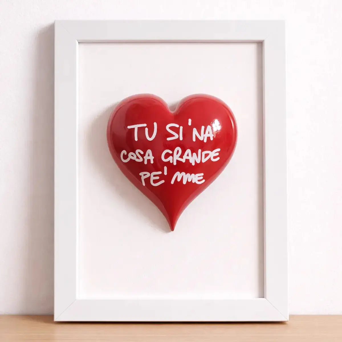 Quadretto CuoreAmore fatto a mano in Italia. Ha una cornice in legno bianca e un cuore in ceramica rosso con una scritta  