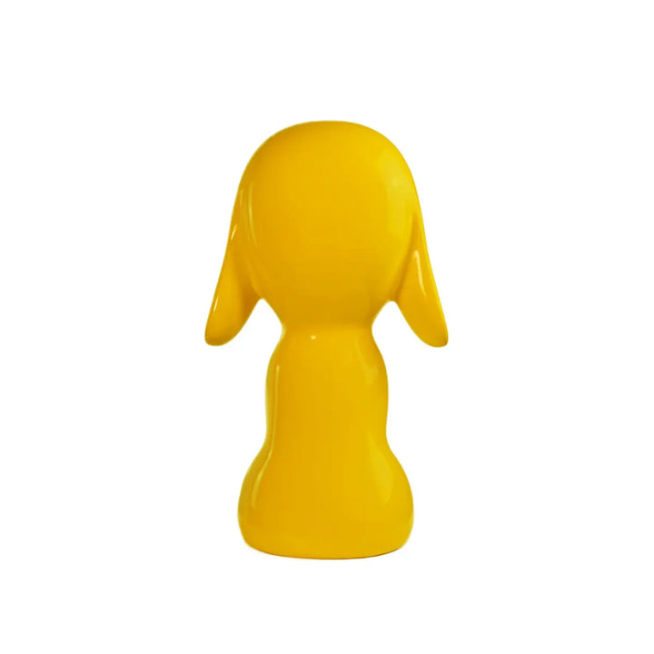 Retro statua gialla a forma di cane, con occhi naso e bocca. Sfondo bianco