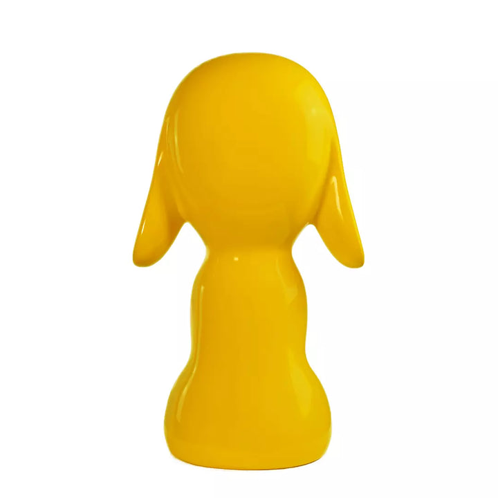 Retro statua gialla a forma di cane, con occhi naso e bocca. Sfondo bianco
