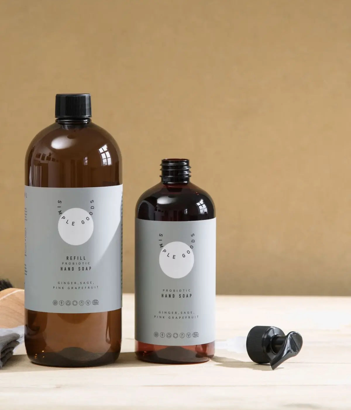 Due bottiglie marroni con etichetta verde. Refill e dispencer sapone mani. Sfondo tavolo bianco