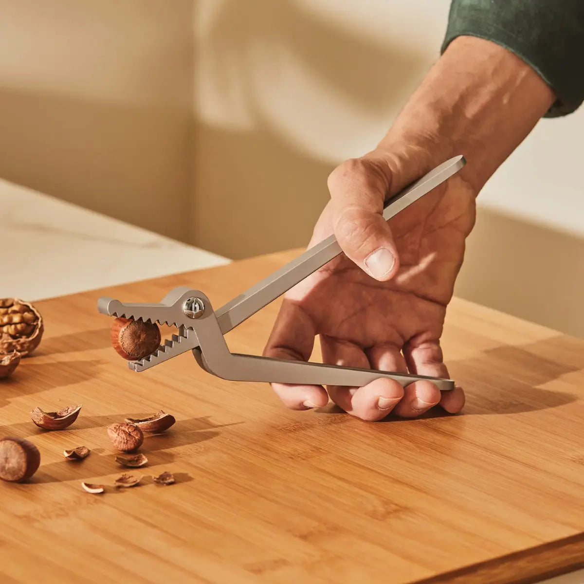Schiaccianoci a forma di coccodrillo Alessi utilizzato da una mano maschile