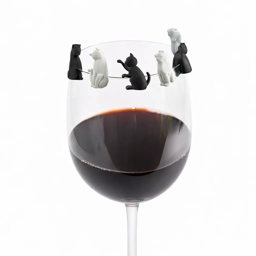 Segnaposto a forma di gatto bianco e nero su bicchiere che contiene vino. Sfondo bianco