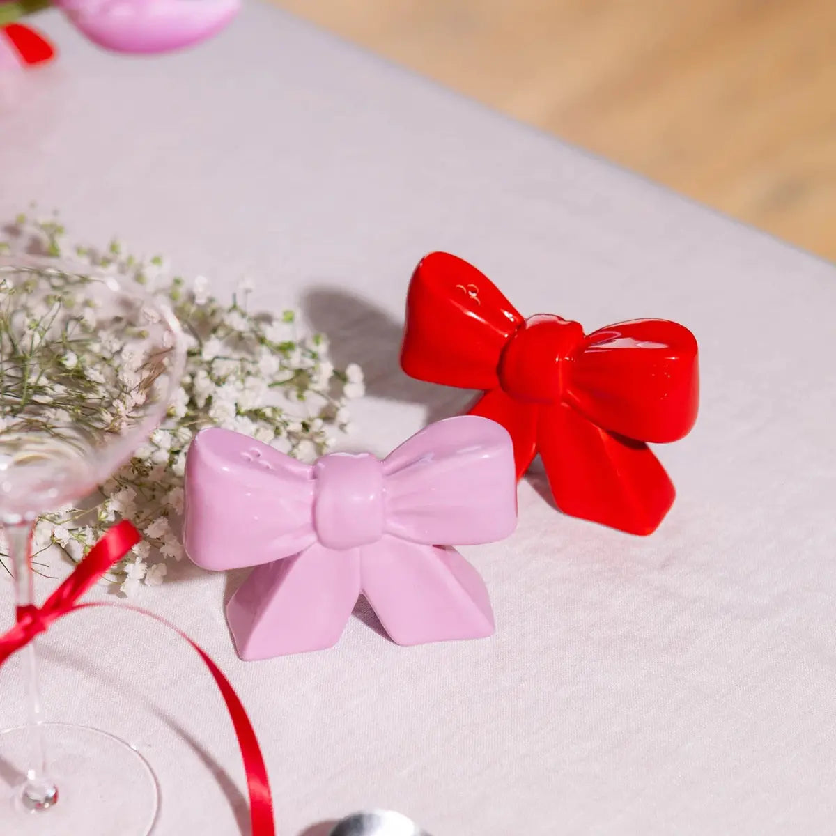 Due fiocchi in ceramica rosso e rosa su un tavolo con tovaglia di tessuto. 