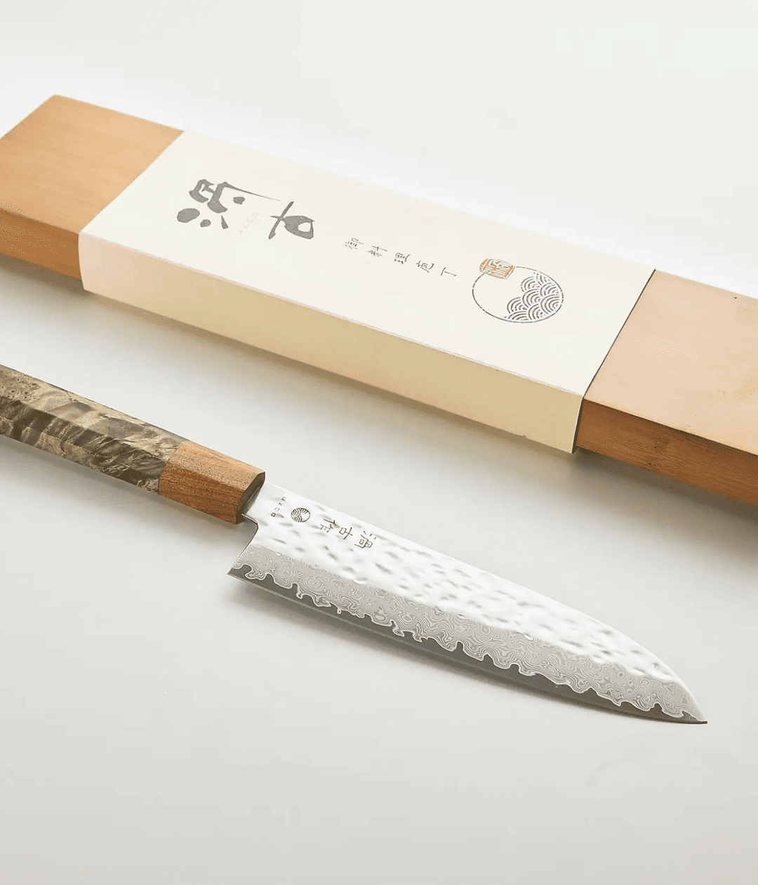 Lama con scritta Giapponese e lavorazione Tsuchime. Scatola in legno. Immagine su sfondo bianco.