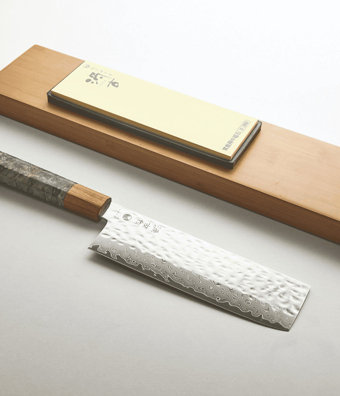 Lama lavorata Tsuchime con scritta, manico verde in legno. Piastra per affilare. Sfondo bianco