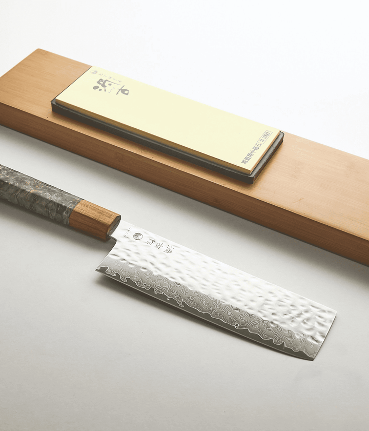 Lama lavorata Tsuchime con scritta, manico verde in legno. Piastra per affilare. Sfondo bianco