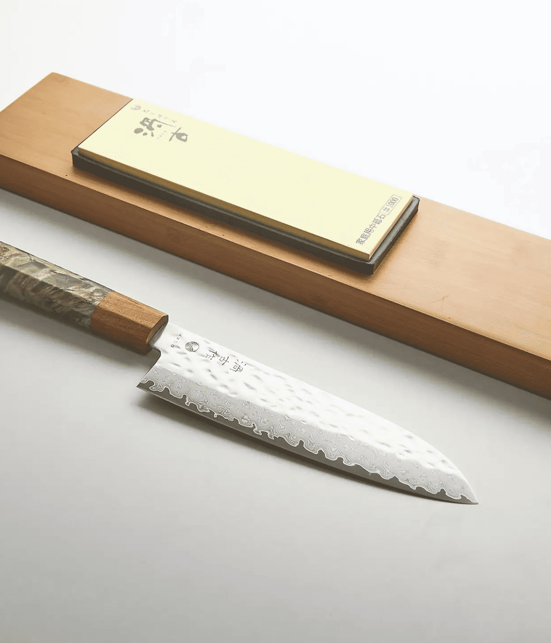 Lama lavorata Tsuchime con scritta, manico verde in legno. Piastra per affilare. Sfondo bianco