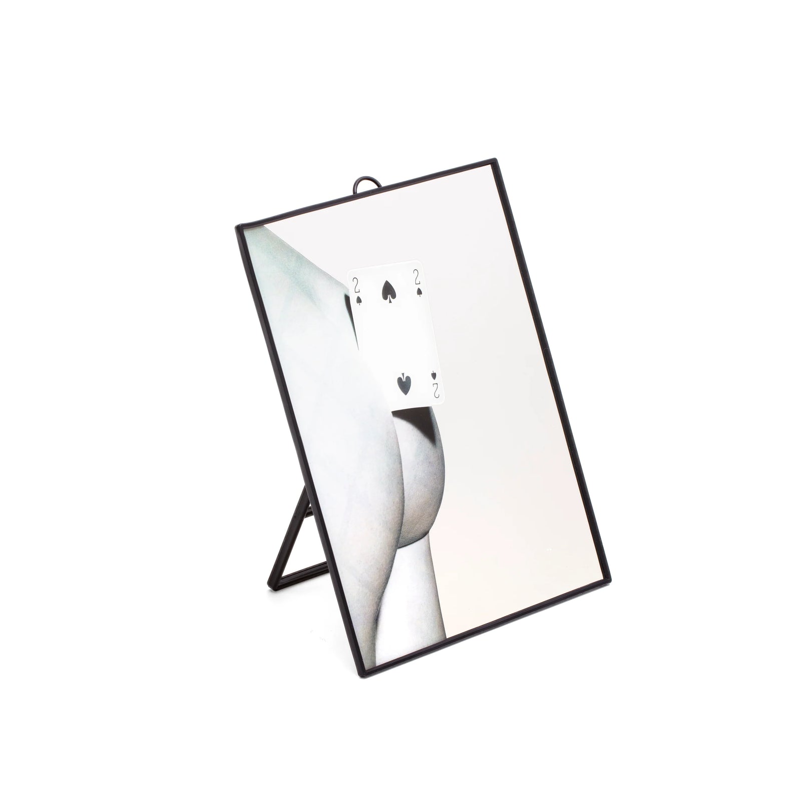 Vista laterale dello specchio della collezione Toiletpaper di Seletti rappresentate un fondoschiena con una carta due di picche. La cornice e il supporto dello specchio sono in plastica nera