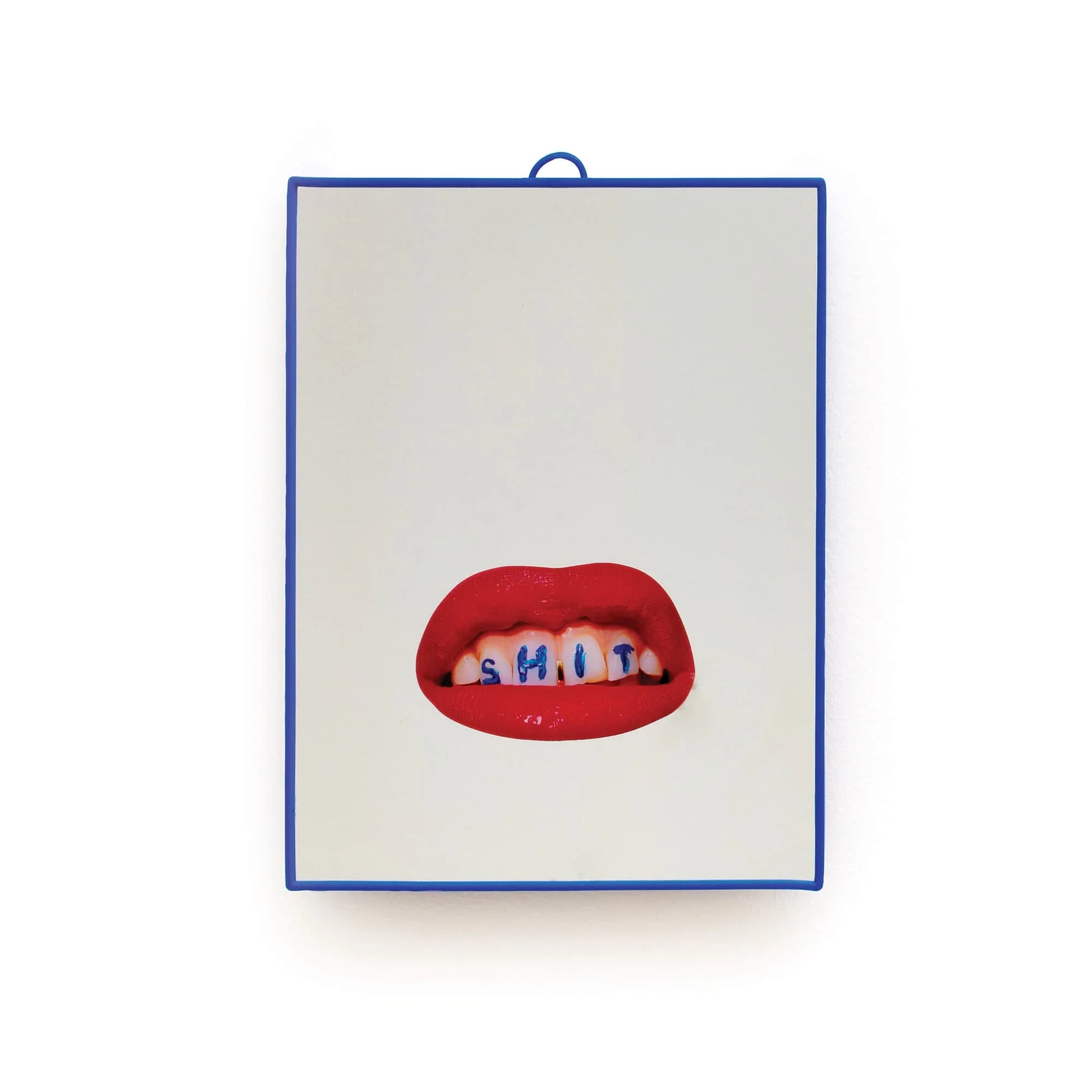 Specchio con grafica "Shit" di Toiletpaper x Seletti. Lo specchio è incorniciato in una cornice di plastica blu e la grafica con le labbra rosse e la scritta shit è posizionata nella parte inferiore dello specchio. Sfondo bianco