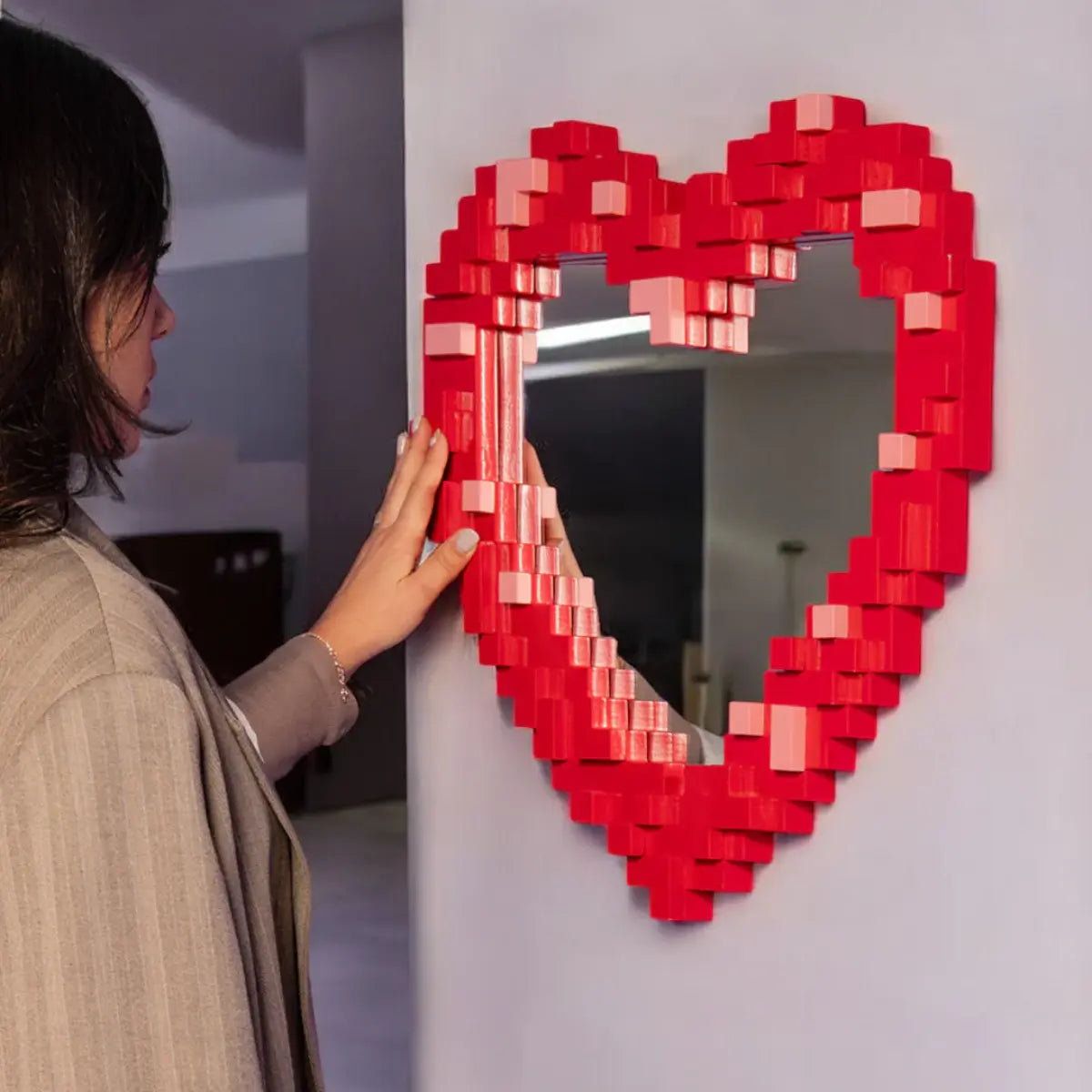 Donna che si specchia nello specchio a forma di cuore con effetto pixel rosso. 