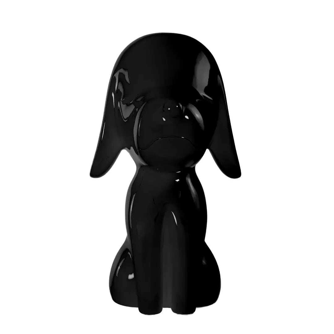 Una statua nera a forma di cane, con occhi naso e bocca. Sfondo bianco