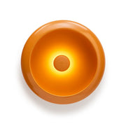Lampada da tavolo/vuotatsche rotonda arancione con luce accesa al centro. Sfondo bianco