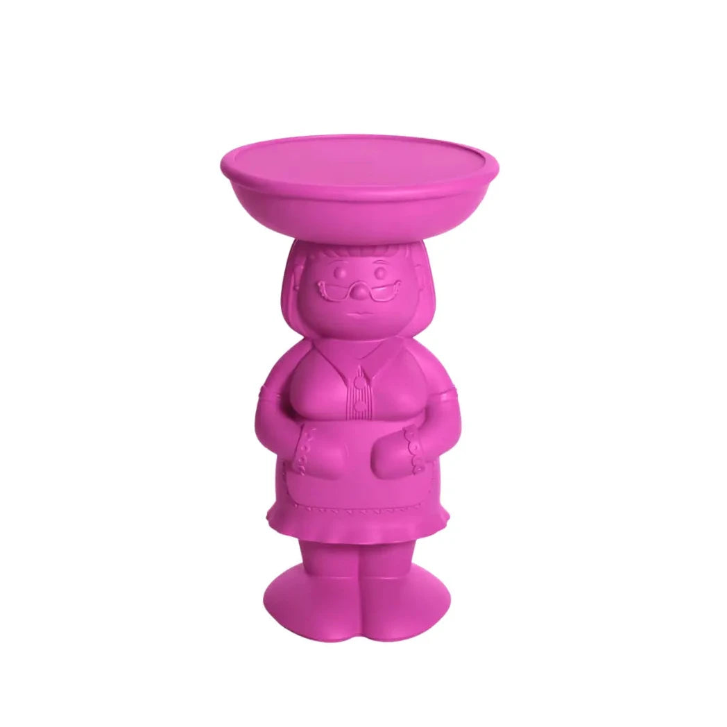 Tavolino fuchsia che rappresenta una donna di casa vestita con grembiule e occhiali con un vassoio appoggiato sulla testa che funge da appoggio del tavolino. Sfondo bianco