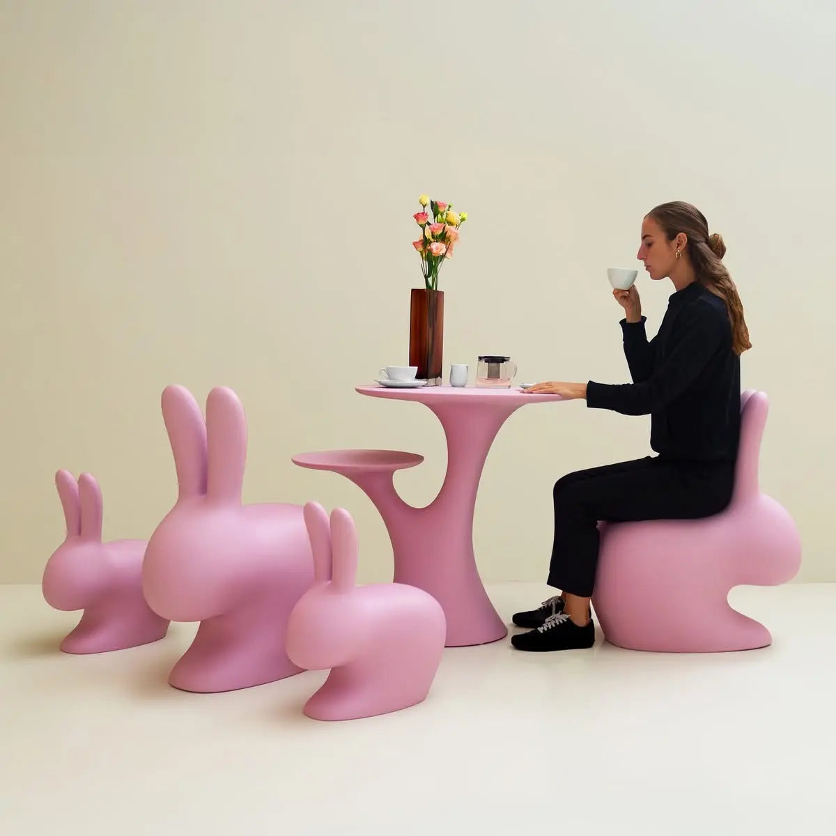 Tavolo che si presenta come un albero con due rami che sorreggono due piani circolari circondato da sedie a forma di coniglio
